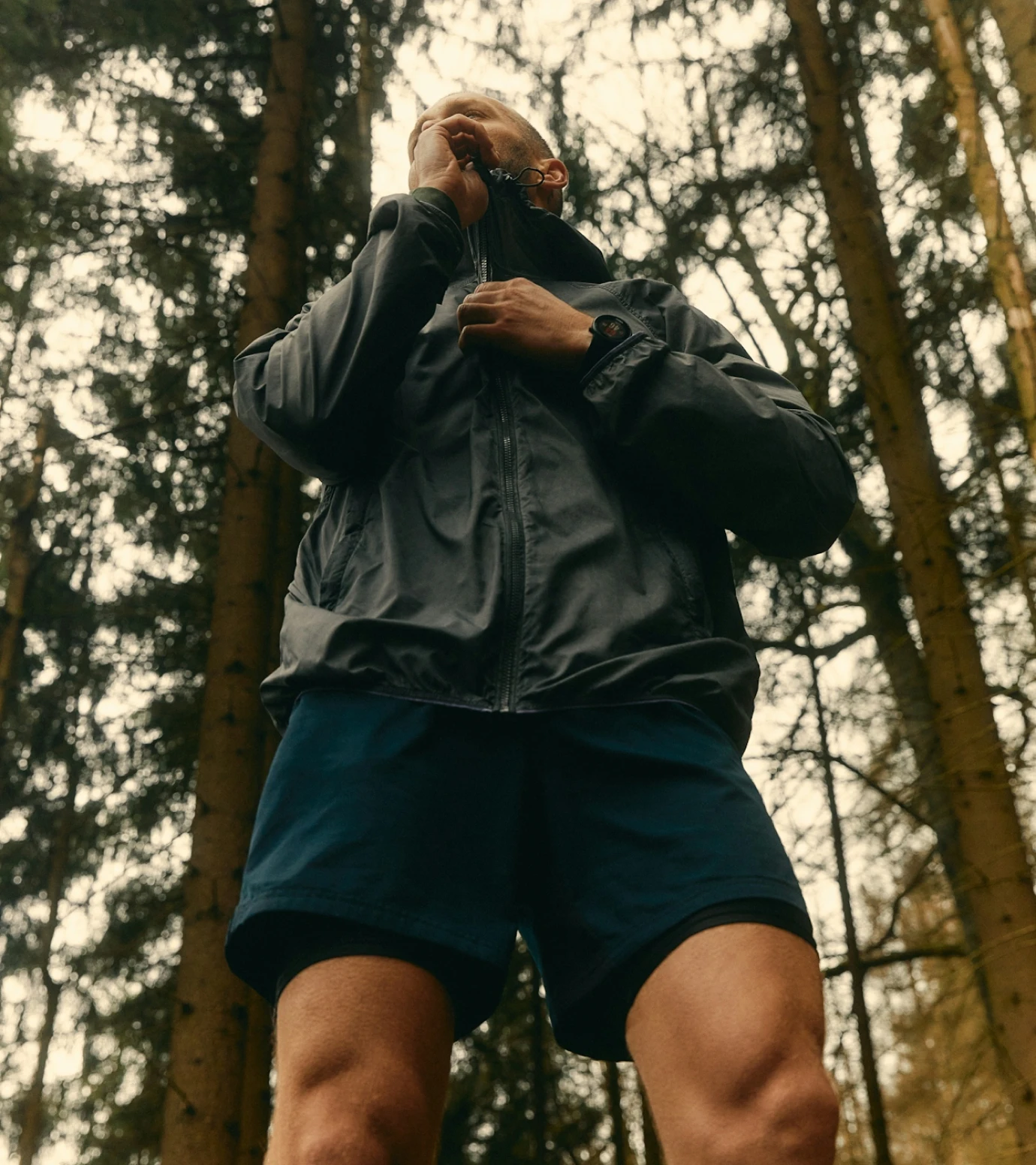 a man standing in the woods talking on a cell phone