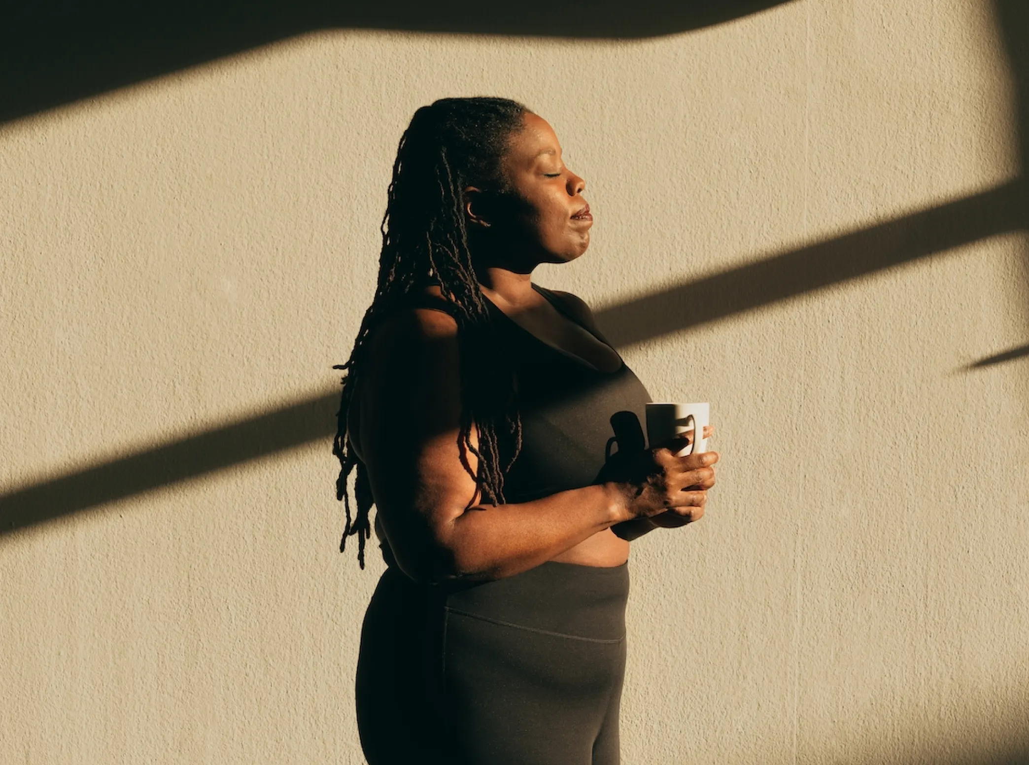 a woman with dreadlocks holding a coffee cup