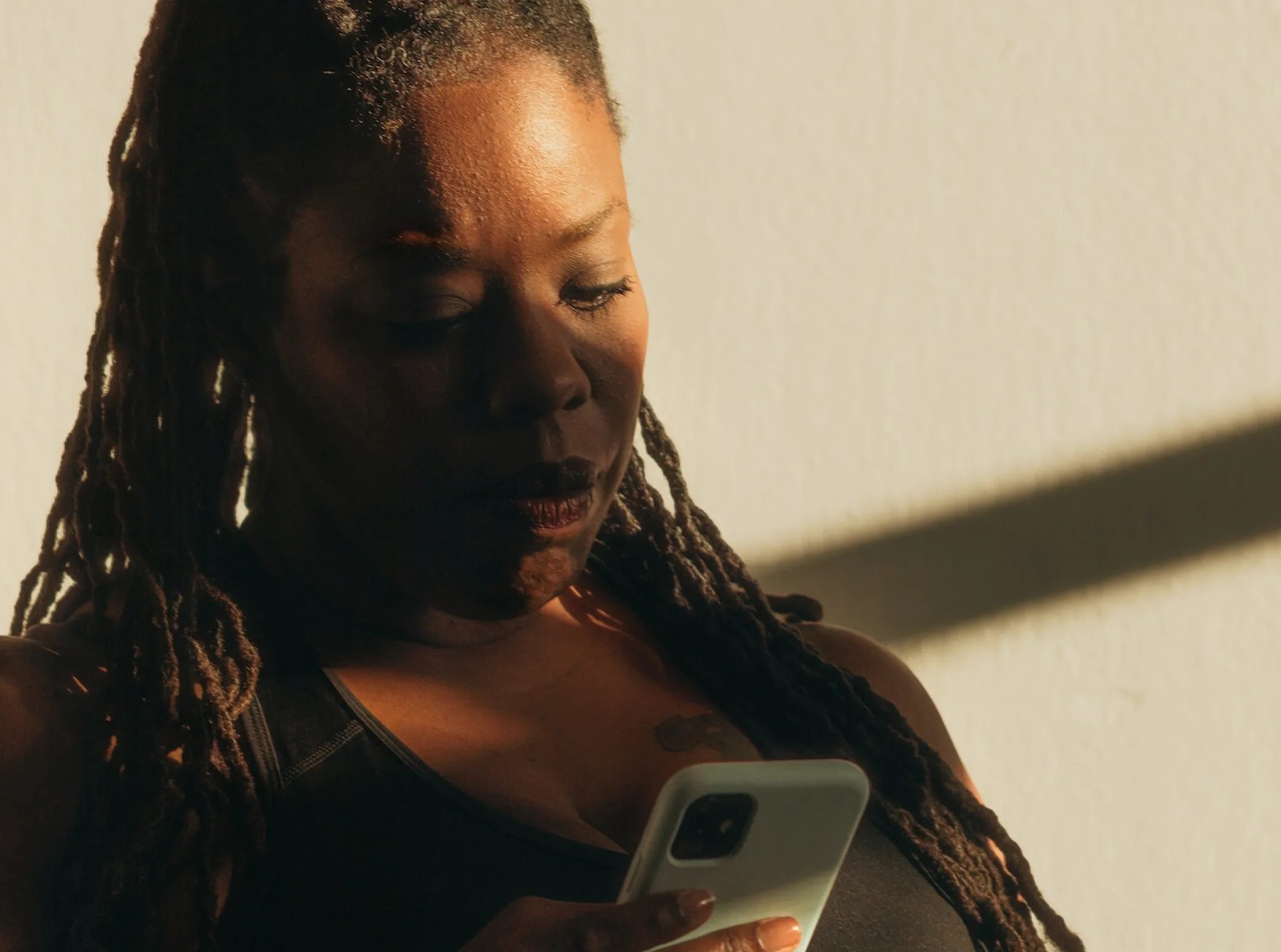 a woman with dreadlocks looking at a cell phone
