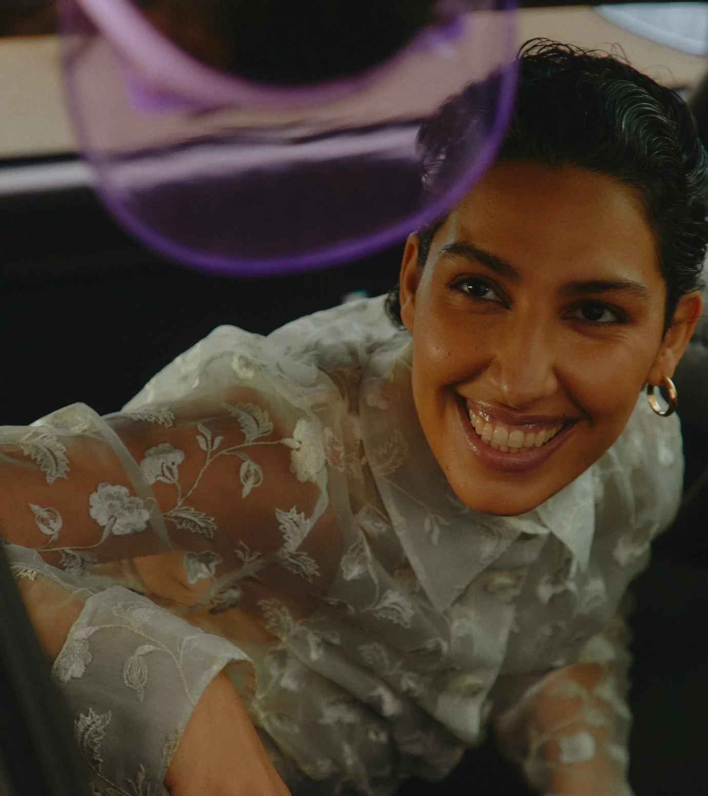 a woman in a white dress smiling in a car