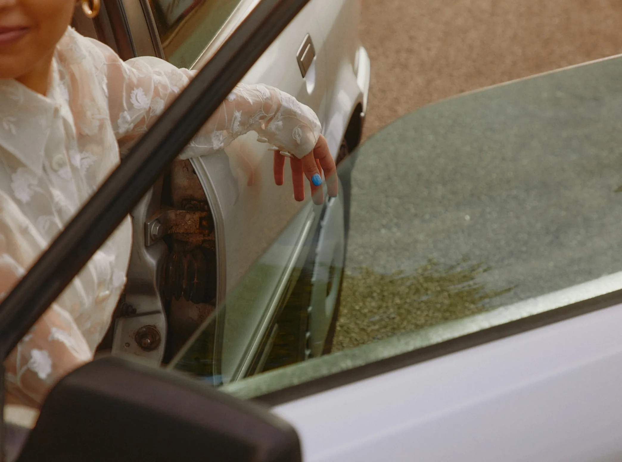 a woman in a white dress getting out of a car