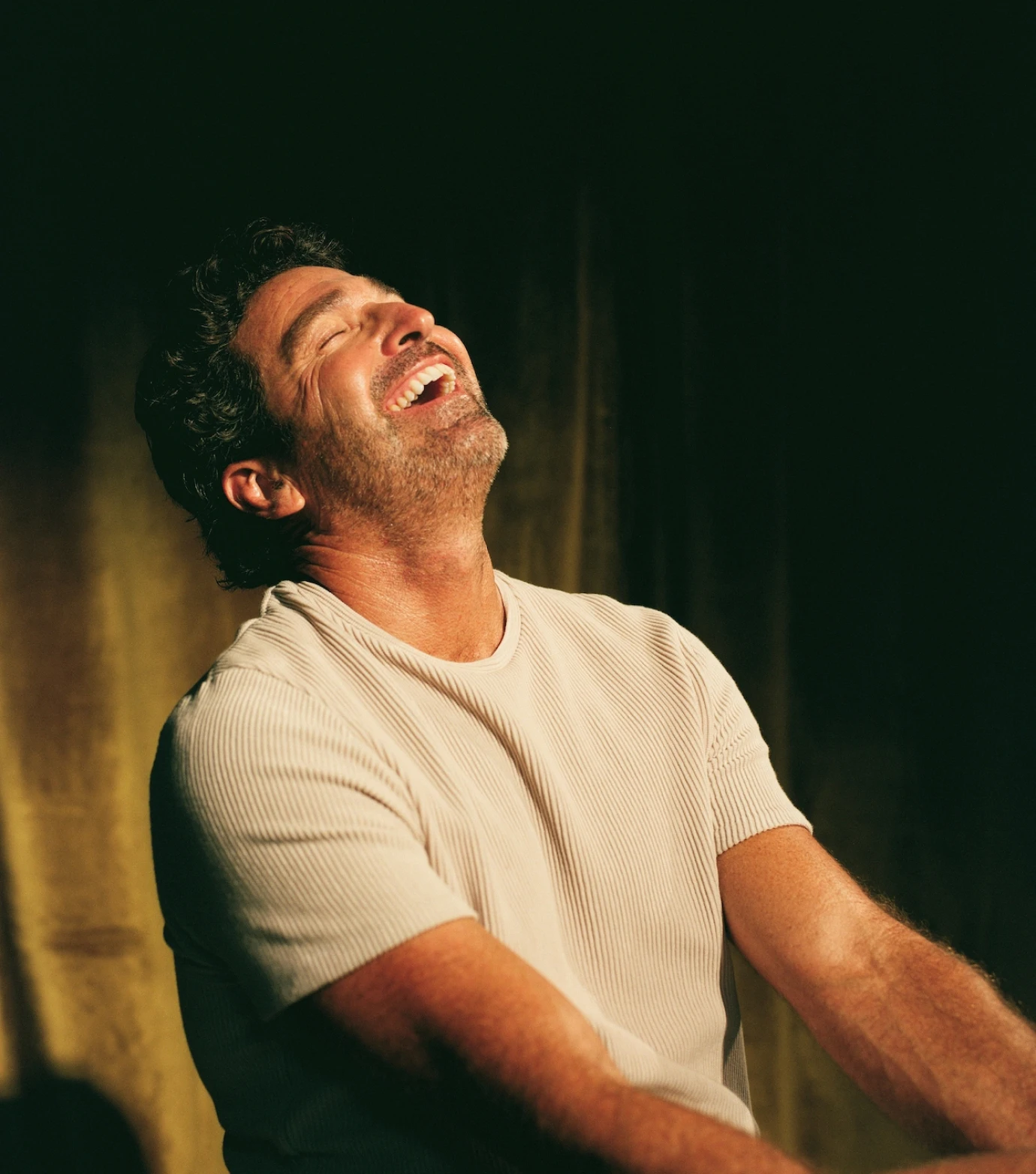 a man laughing while holding a tennis racquet