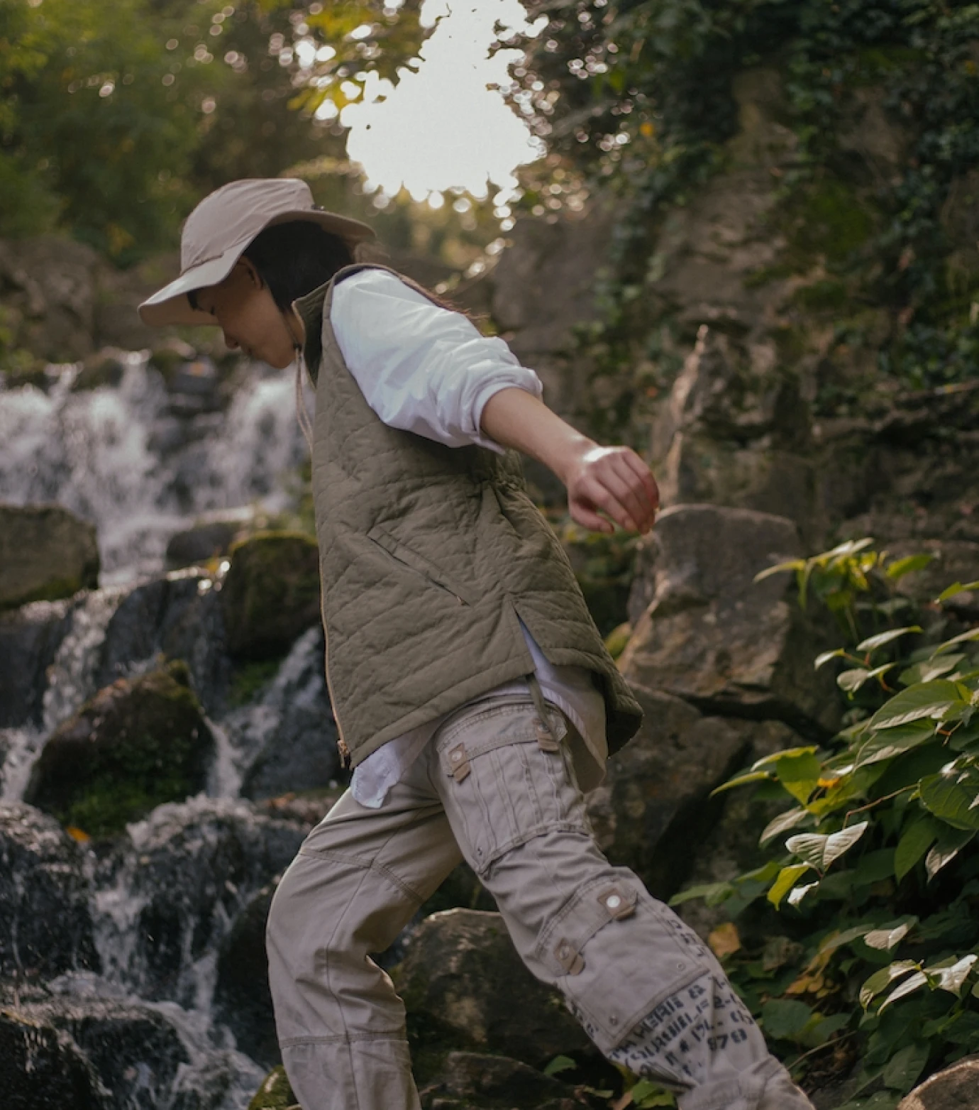 a man walking on a rock near a waterfall